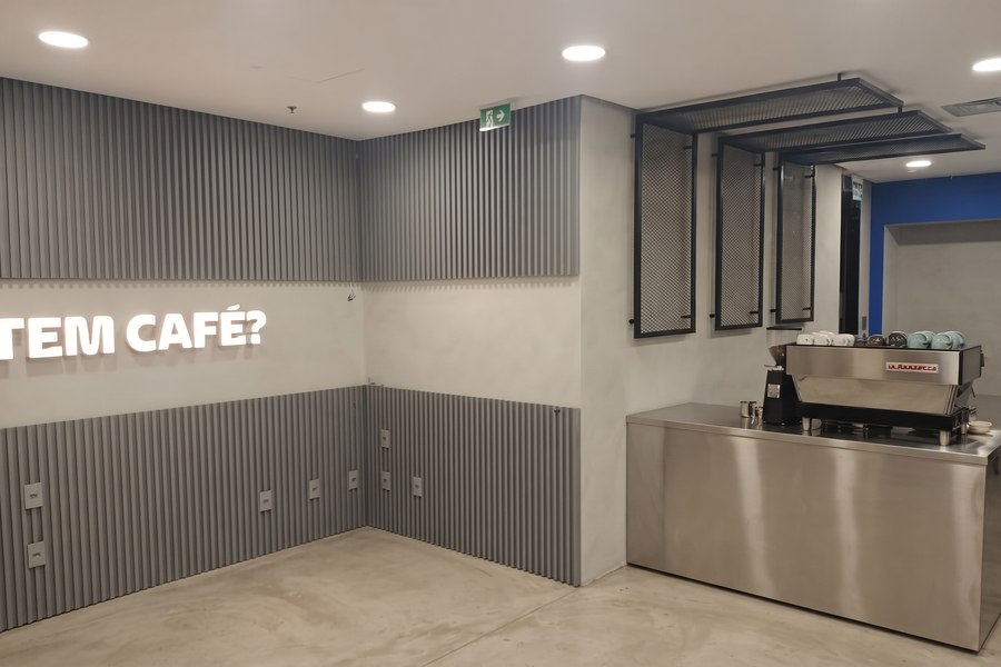 Cafeteria corporativa entregue, com painel ripado, letreiro e máquina de espresso instalada