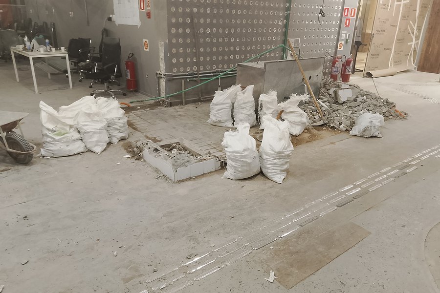Entulho ensacado e área isolada durante retrofit em andar corporativo ocupado