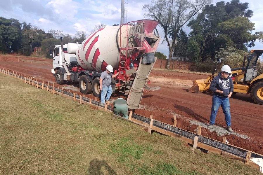 Caminhão betoneira concretando meio-fio com equipe em EPI