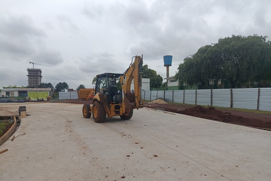 Retroescavadeira regularizando o entorno do pavimento concluído
