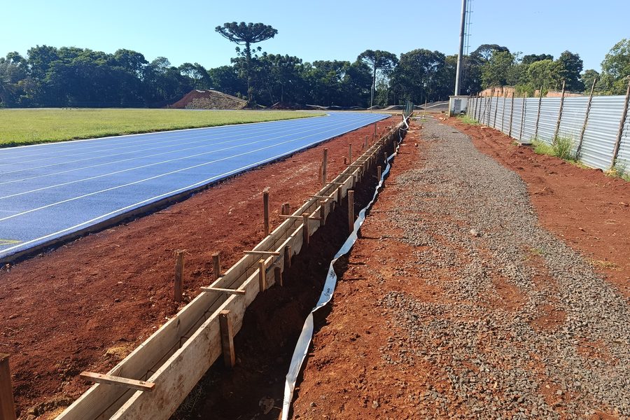Pista recebendo a primeira camada azul com canaleta lateral em execução