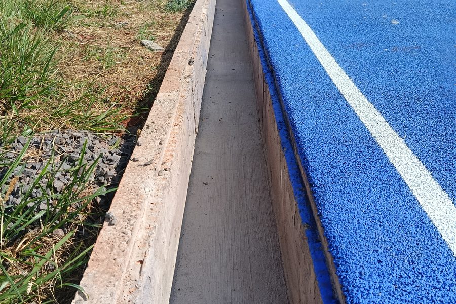 Detalhe do meio-fio branco junto à pista azul