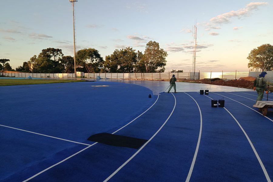 Pista azul ao amanhecer com equipe e postes de iluminação