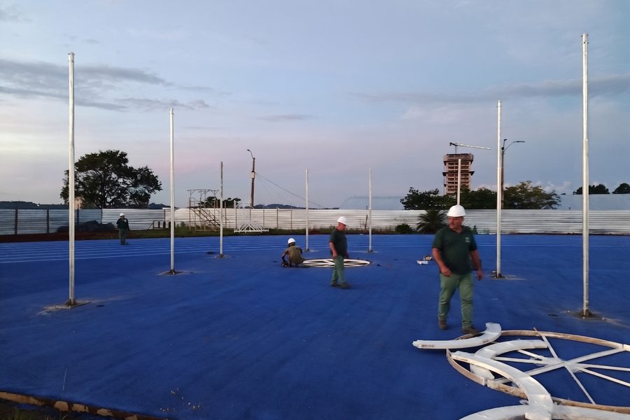 Equipe montando postes e equipamentos esportivos ao entardecer