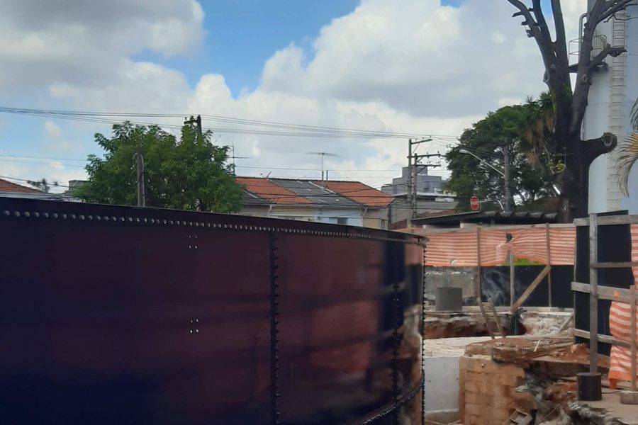 Parede externa escura do reservatório junto à base de concreto