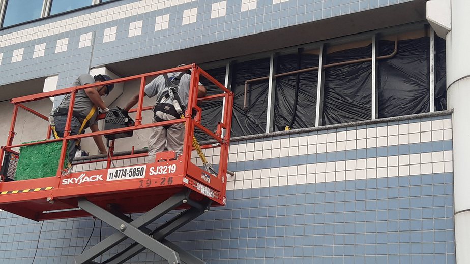 Equipe em plataforma elevatória na fachada farmacêutica