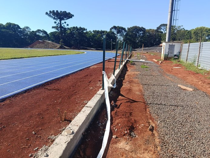 Pista de atletismo em obra, com meio-fio e cerca