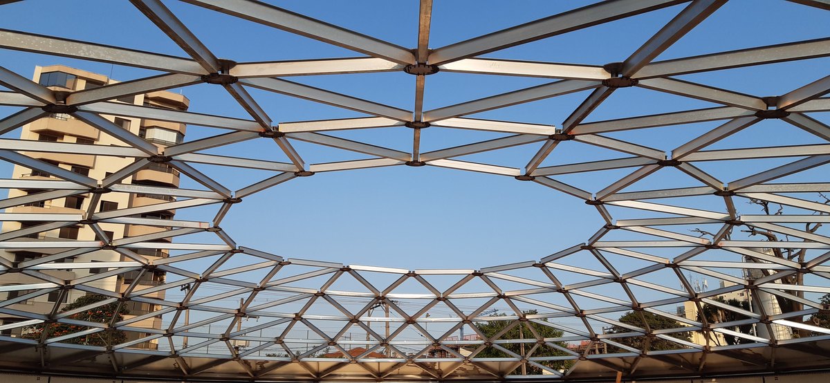 Estrutura triangulada do domo geodésico vista de dentro contra o céu